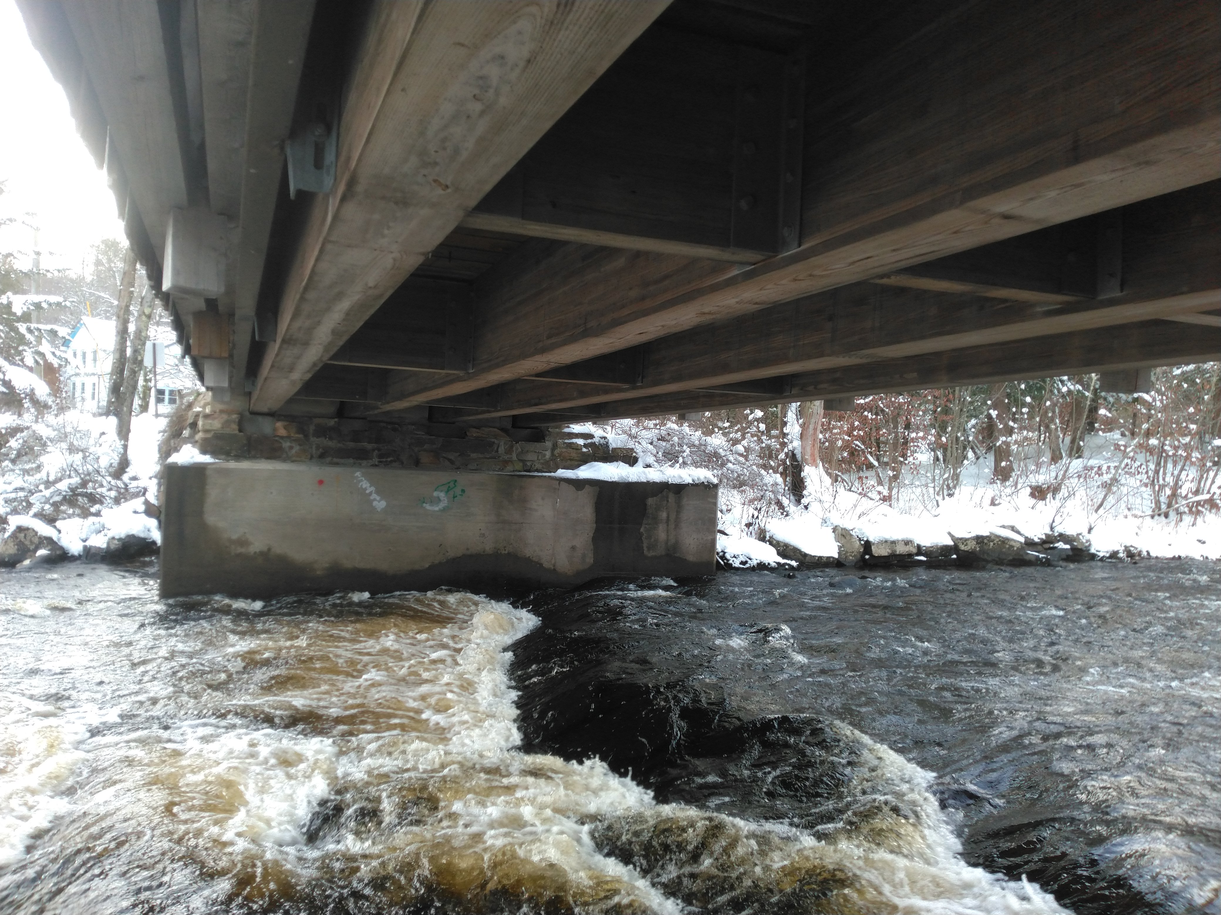 A river under a bridge in the middle of winter with heavy flow. Photo by Isaiah Wood.